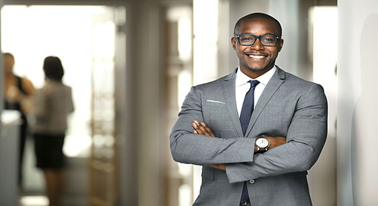 Elegant African businessman standing in office with folded hands.