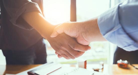 Two men shaking hands in business office.