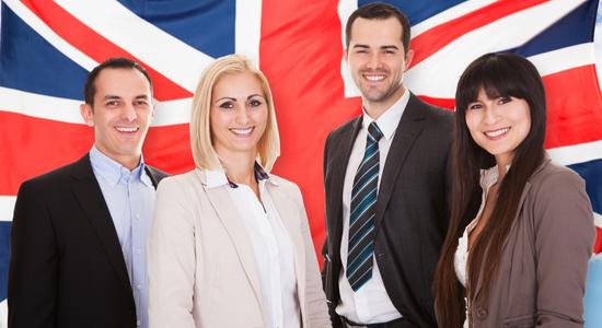 Four businesspeople smiling at camera in front of a Union Jack.