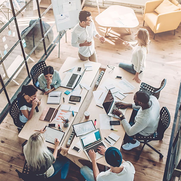 A professional smiling businesswoman standing in office with folded hands.
