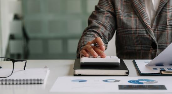 A man holding a pen and working on a calculator. Concept of insurance translation by professional insurance translators.