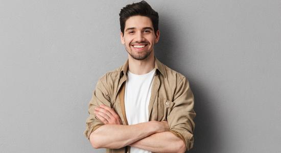 A brunet man in casual clothes smiling at camera. 