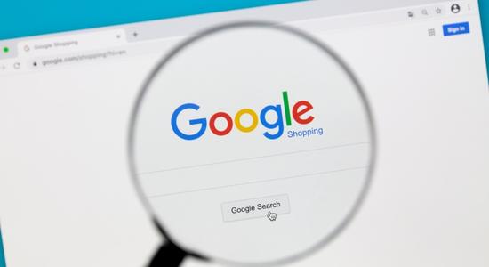 A magnifying glass above a screen showing the Google search engine homepage. 