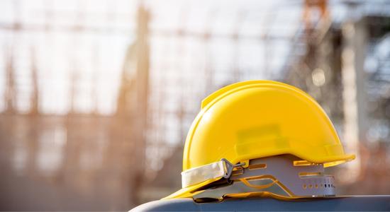A yellow helmet in focus, construction site in the background.