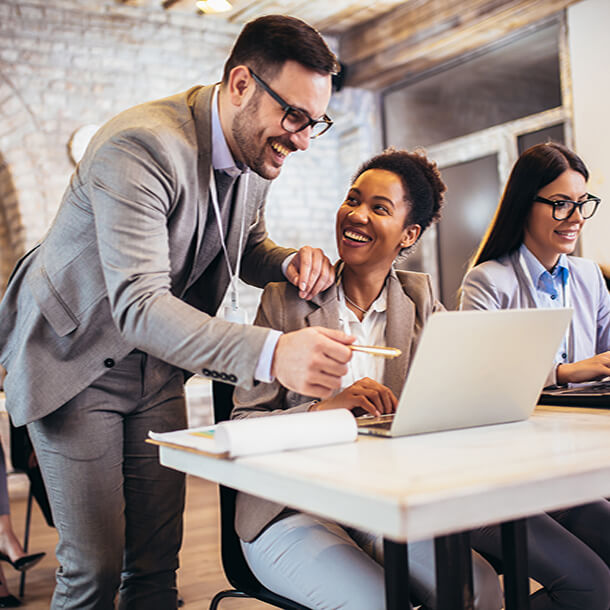 A professional smiling businesswoman standing in office with folded hands.