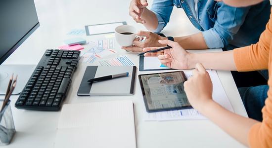 Two people working on table with mobiles and computer. Concept of app translators.