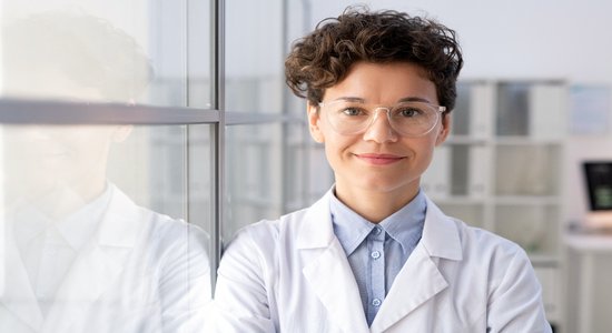 A female scientist in lab gear smiling at the camera. Concept of scientific translators.     