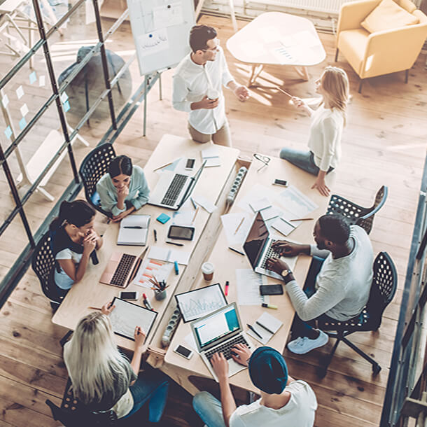 A professional smiling businesswoman standing in office with folded hands.