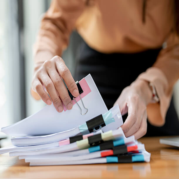 A professional smiling businesswoman standing in office with folded hands.