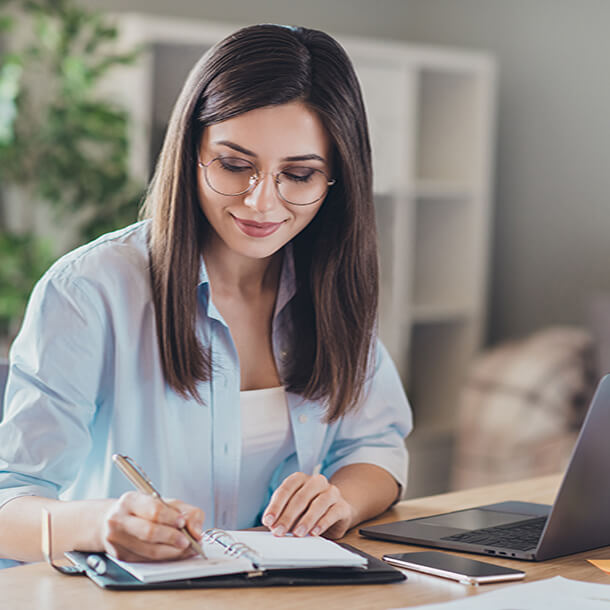 A professional smiling businesswoman standing in office with folded hands.
