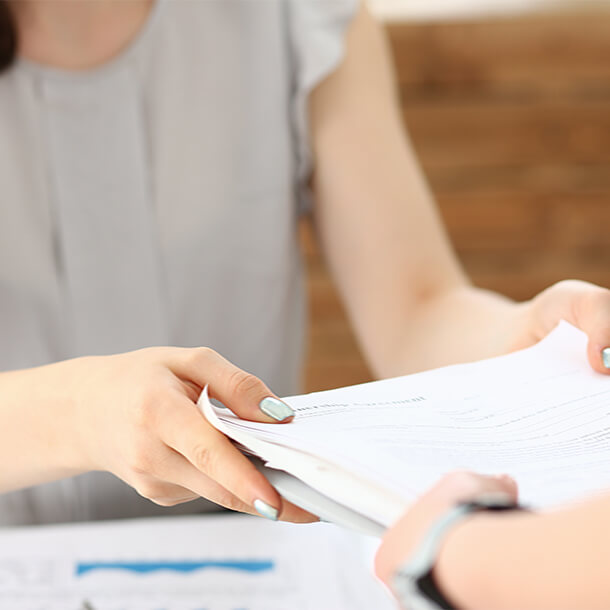 African man wearing suit and glasses smiling and signing paper.