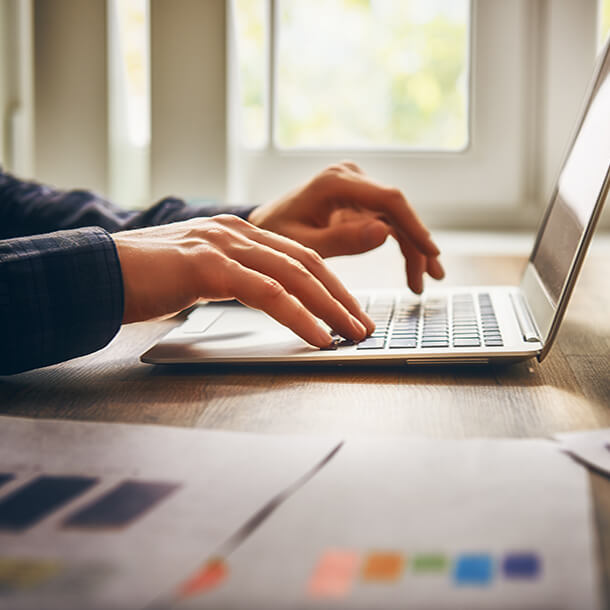 African man wearing suit and glasses smiling and signing paper.