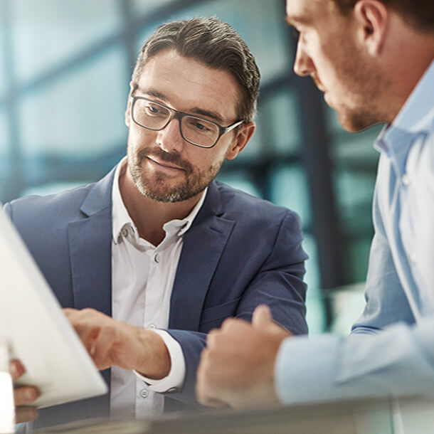 African man wearing suit and glasses smiling and signing paper.