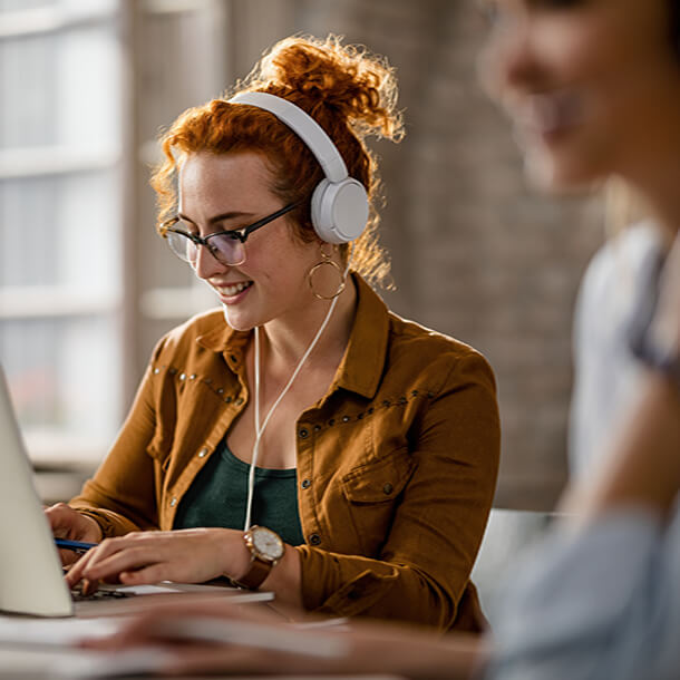 African man wearing suit and glasses smiling and signing paper.