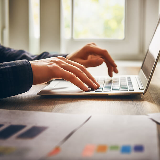 Two young employees celebrate success by giving high-five while their colleagues sitting and smiling. 
